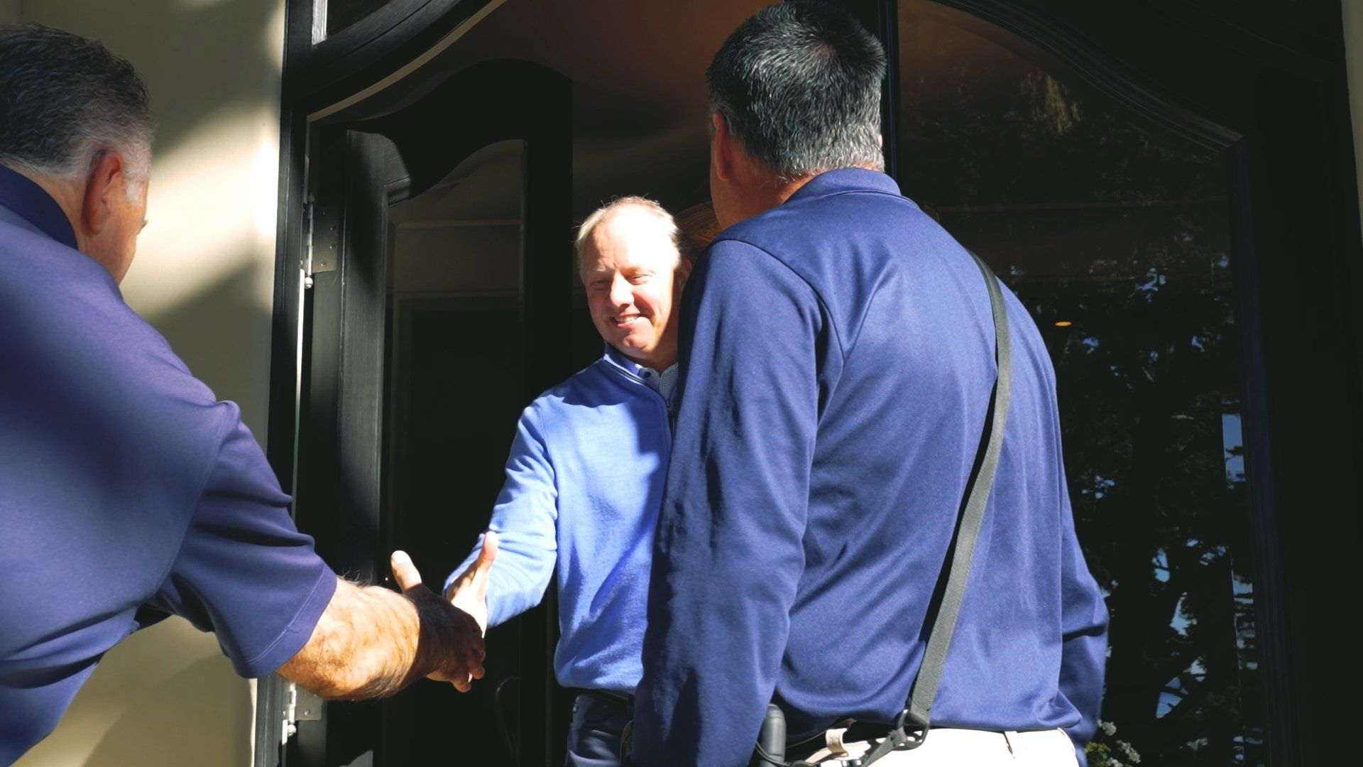 Two men, including a real estate agent, shaking hands in front of a door, representing a successful property deal.