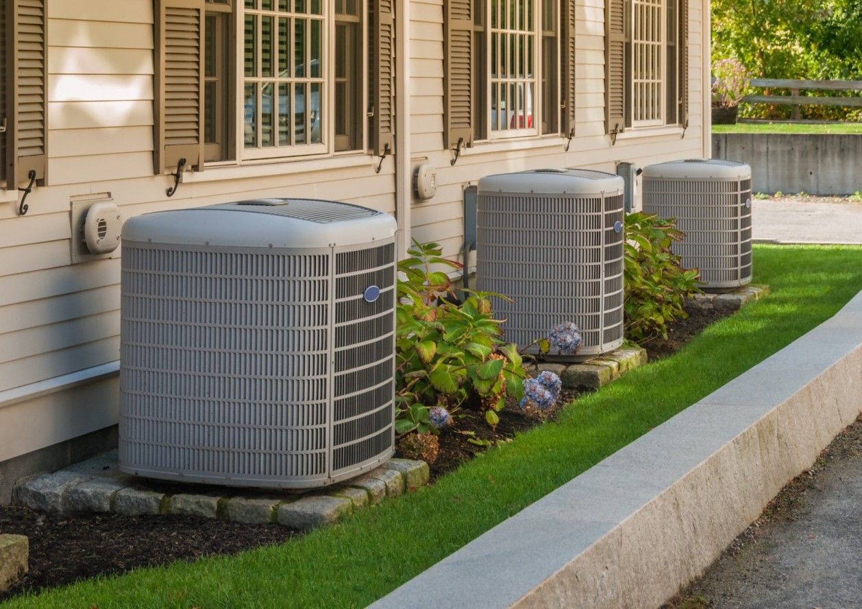 Multiple outdoor HVAC condenser units installed beside a residential home, representing energy-efficient heating and cooling systems for improved home comfort.